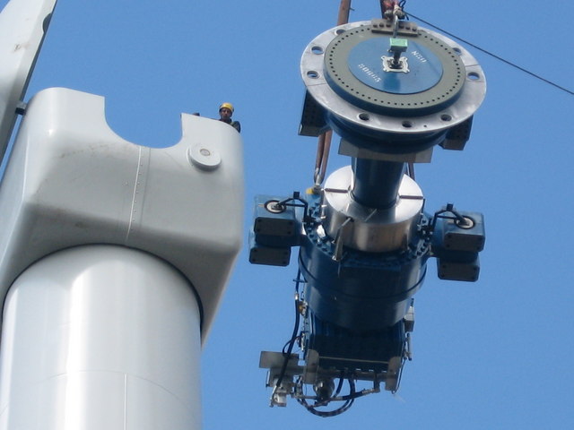 At 60 metres up from the ground the crane lifts the huge 12 ton gearbox and disk brake assembly in to position. The engineer stood in the nacelle is in contact by radio with the crane operator below
